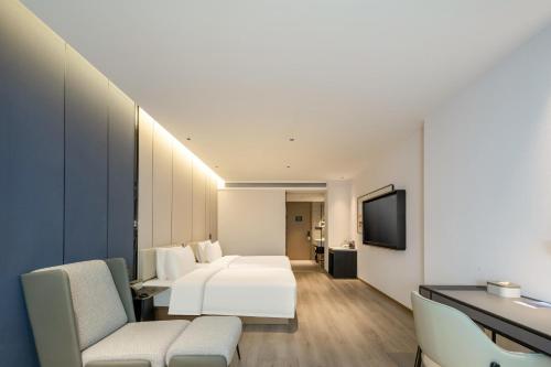 um quarto de hotel com uma cama e uma televisão em Atour Hotel Luqiao Taizhou em Taizhou