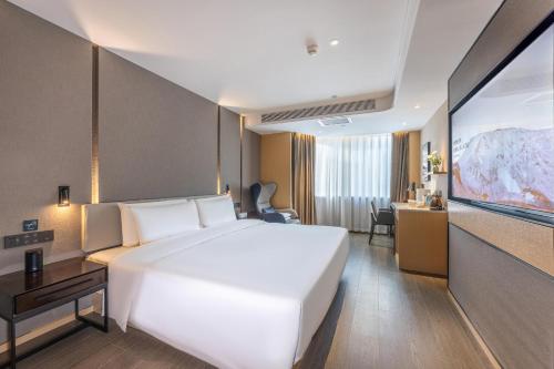 Atour Hotel Lanzhou Railway Bureau في لانتشو: سرير أبيض كبير في غرفة الفندق