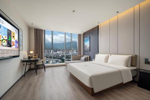 una camera da letto con un grande letto bianco e una grande finestra di Atour Hotel Dali Erhai Park a Dali