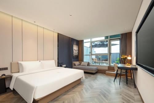 Un dormitorio con una gran cama blanca y un sofá. en Atour Hotel Tonglu City Center Hangzhou, en Xiaoba