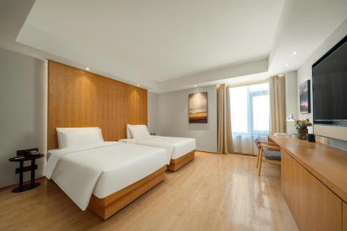 a hotel room with two beds and a flat screen tv at Atour X Hotel Wuxi Binhu Sports Center in Wuxi