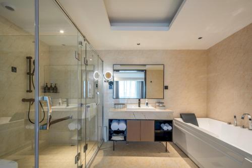 uma casa de banho com um lavatório, uma banheira e um chuveiro em Atour X Hotel Hangzhou Wenyi Road em Hangzhou