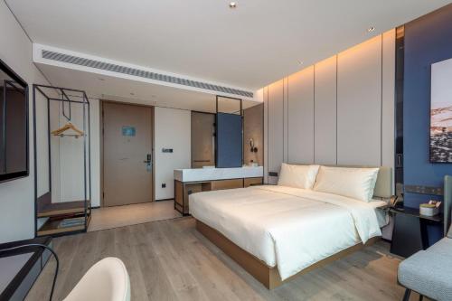 a bedroom with a large white bed and a television at Atour Hotel Hangzhou East Railway Station West Square in Hangzhou