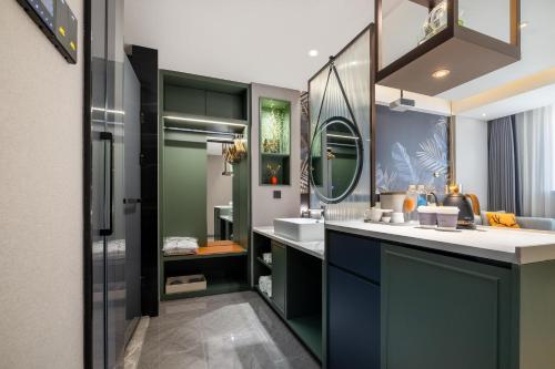 La salle de bains est pourvue d'un lavabo et d'un miroir. dans l'établissement Atour X Hotel Yulin Changcheng Road Confucius Temple, à Yulin