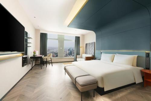 Atour S Hotel Lanzhou Asia-Europe International High Altitude في لانتشو: غرفة نوم بسرير ابيض كبير وغرفة معيشة
