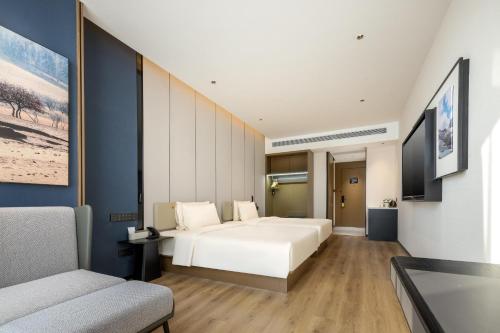 een slaapkamer met een wit bed en een bank bij Atour X Hotel Changzhou Jintan District Government in Jintan