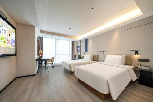 a hotel room with two beds and a television at Atour X Hotel Hangzhou Wenyi Road in Hangzhou