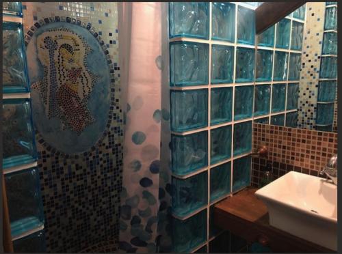 La salle de bains est pourvue d'un lavabo et d'une douche avec du carrelage bleu. dans l'établissement casa rural LAS CHIMENEAS, à Casasimarro