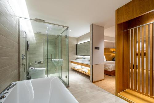 a bathroom with a tub and a shower and a bedroom at Atour X Hotel Wuxi Binhu Sports Center in Wuxi