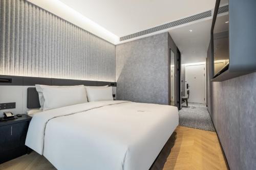 - une chambre avec un grand lit blanc et un couloir dans l'établissement Atour Light Hotel Shanghai Minhang Maqiao, à Shanghai