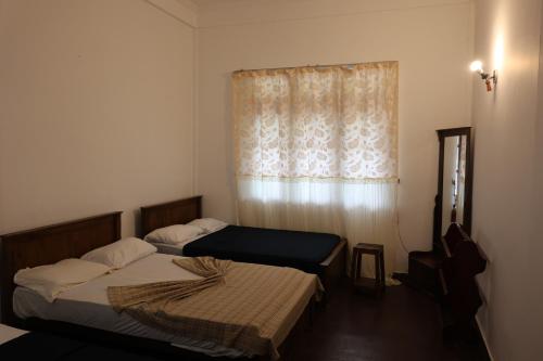 two beds in a room with a window at Paramount Hotel Pussellawa in Pussellawa