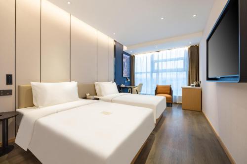 a hotel room with two beds and a flat screen tv at Atour X Hotel Yanji Department Store West Market in Yanji
