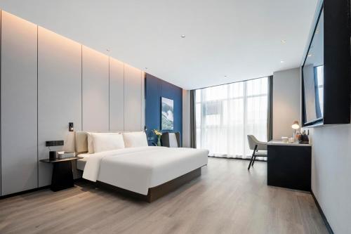 a bedroom with a large white bed and a desk at Atour Hotel Huaihua High-Speed South Railway Station in Huaihua