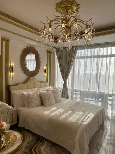 een slaapkamer met een groot wit bed en een kroonluchter bij Gramercy Residences Makati Hidden Gem in Makati