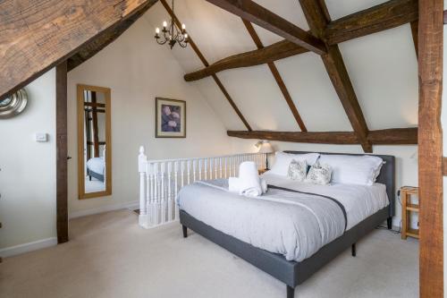 a bedroom with a white bed with wooden ceilings at Box Cottage in Broadwell