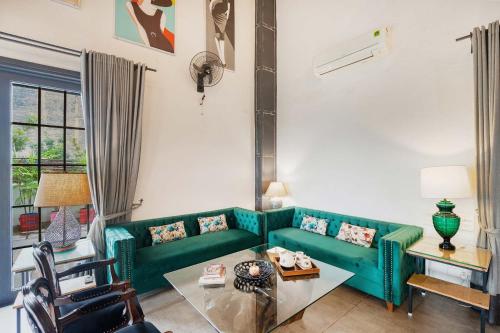 a living room with a green couch and a table at StayVista's The Barn House - Farm-View Villa with with bonfire, Indoor Pool & Bar in Chandīgarh