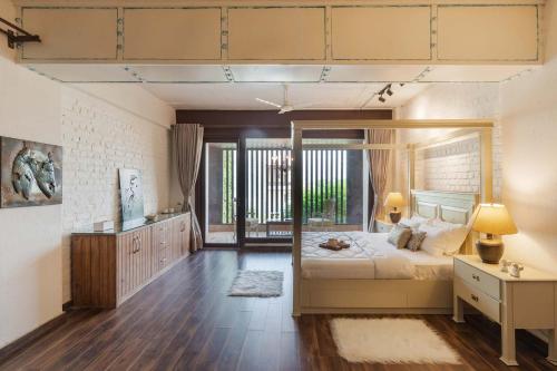 Un dormitorio con una cama grande y una ventana en StayVista's The Barn House - Farm-View Villa with Modern Rustic Interiors, Indoor Pool & Bar, en Chandīgarh