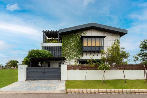 a white house with a black roof at StayVista's The Barn House - Farm-View Villa with with bonfire, Indoor Pool & Bar in Chandīgarh