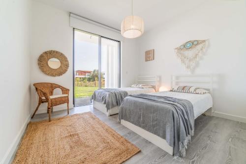 2 Betten in einem weißen Zimmer mit Fenster in der Unterkunft Villa Arrabida in Quinta do Conde