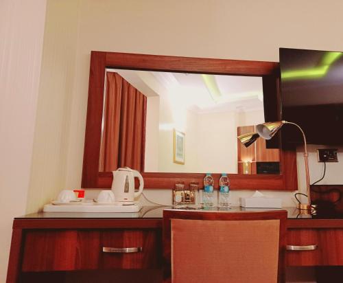 a mirror on a desk with a sink and a lamp at Royal Qatar Hotel in Doha