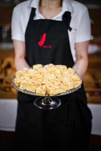 a woman is holding a pie on a plate at Hotel SLUNEČNÁ LOUKA in Lipno nad Vltavou