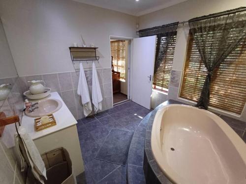 a bathroom with a tub and a sink at Khalila's Equestrian Cottage in Midrand