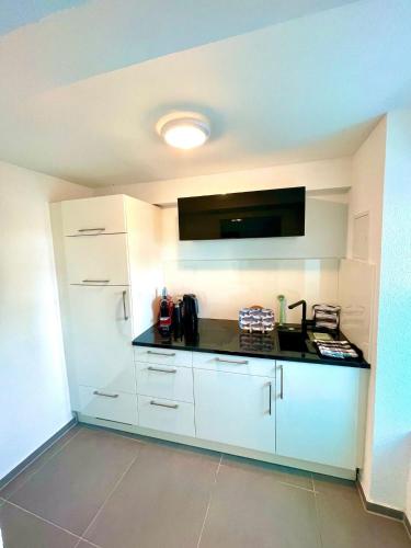 a kitchen with white cabinets and a black counter top at Ferienwohnung direkt am Bodensee / Untersee nahe Konstanz in Berlingen