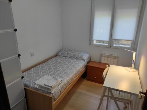 Habitación pequeña con cama y escritorio. en Precioso apartamento con patio, en Zamora