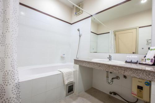 a bathroom with a sink and a tub and a mirror at Baiyoke Ciao Hotel in Chiang Mai