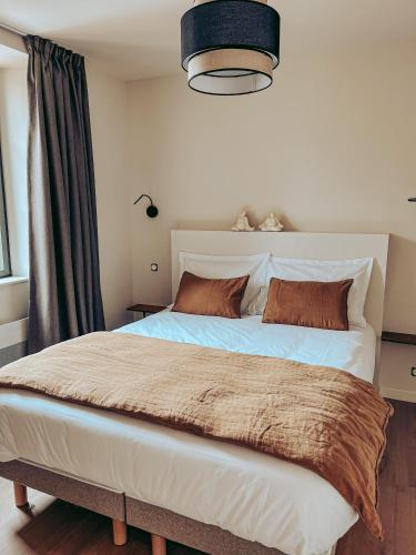 a bedroom with a large bed with brown pillows at Domaine du Mimosa in Perros-Guirec
