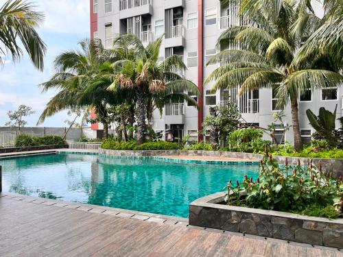 a swimming pool in front of a building with palm trees at VidaView Apart for Family Syariah by NAD in Pampang