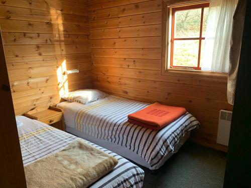 a bedroom with two beds in a log cabin at Chalet 17 tournesol Mauroux in Mauroux