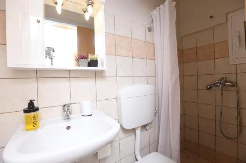 W łazience znajduje się umywalka, toaleta i lustro. w obiekcie Andromache's w mieście Gastouri
