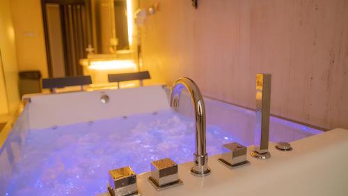 a bathroom with a tub with blue water and a faucet at Al Qand Chalet For Families Only in Half Moon Bay