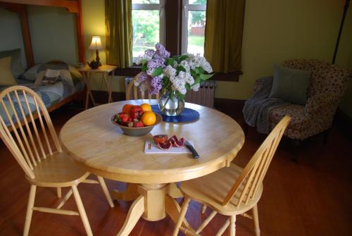 a table with a bowl of fruit and a vase of flowers at Victoria Falls Guest House in Nelson