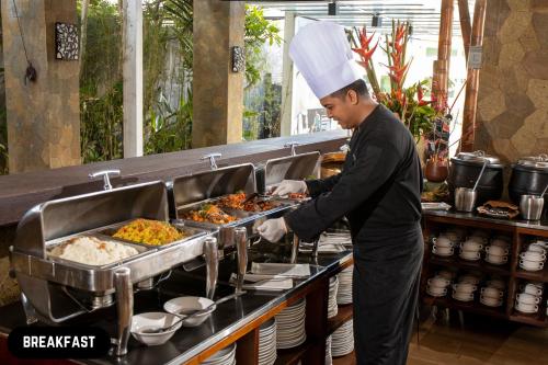 Ein Mann mit Kochmütze bereitet Essen zu in der Unterkunft Grand Ixora Kuta Resort in Kuta