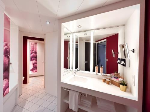uma casa de banho com um lavatório e um espelho grande em Mercure Reims Centre Cathédrale em Reims