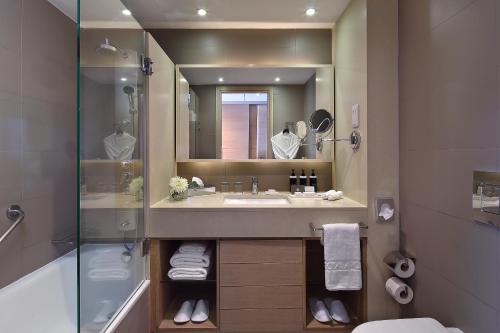 a bathroom with a sink and a shower and a mirror at Royal Apollonia by Louis Hotels in Limassol