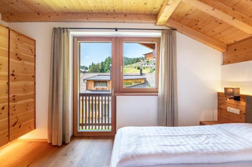 a bedroom with a bed and a large window at Villa Solinda App Puccini in Selva di Val Gardena