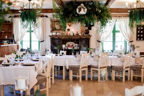 a dining room with white tables and chairs at Osada Między Drzewami in Braniewo