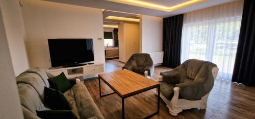 a living room with a couch and chairs and a television at Apartamenty Rzucewska 87 in Żelistrzewo