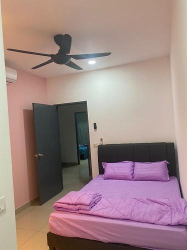 a bedroom with a bed with purple sheets and a ceiling fan at ZZZ HOMESTAY SKUDAI in Skudai