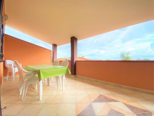 a balcony with a green table and chairs on it at SU BISU Costa Rei R4991 terrace with sea view, 500m from the beach in Costa Rei