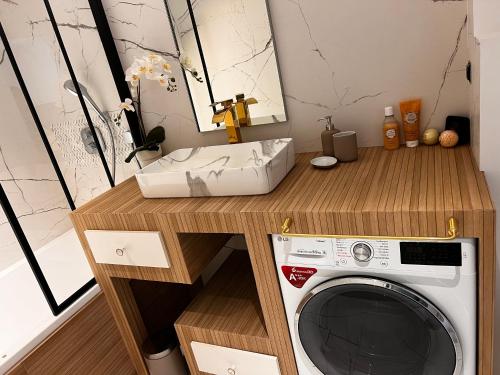 uma lavandaria com uma máquina de lavar roupa e um lavatório em House Prestige em Juvignac