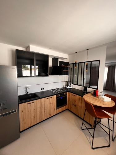 a kitchen with wooden cabinets and a table and a refrigerator at House Prestige in Juvignac