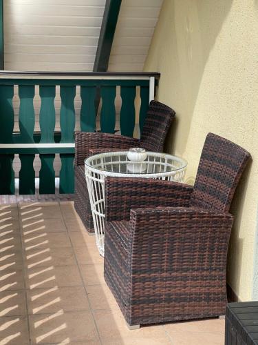 two wicker chairs and a table on a porch at Pension Hühnermühle in Volkerode