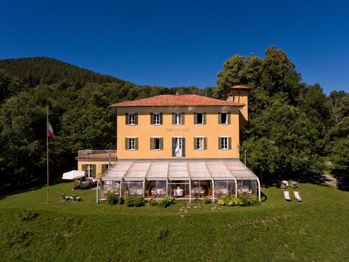 un grand bâtiment sur un champ herbeux avec une maison dans l'établissement Hotel Villa Simplicitas, à San Fedele Intelvi