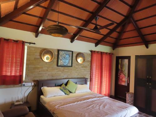 a bedroom with a bed in a room with red curtains at Misty Hills Retreat in Coimbatore