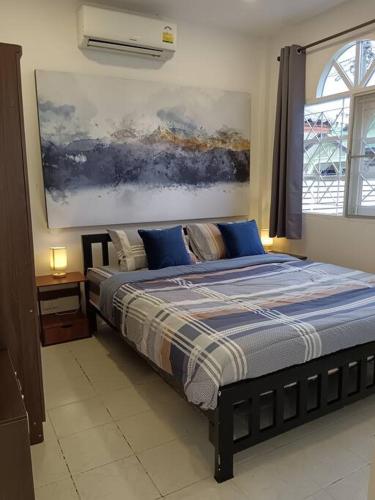 a bedroom with a bed with blue pillows and a painting at Karon Holiday Home by Bcare in Karon Beach