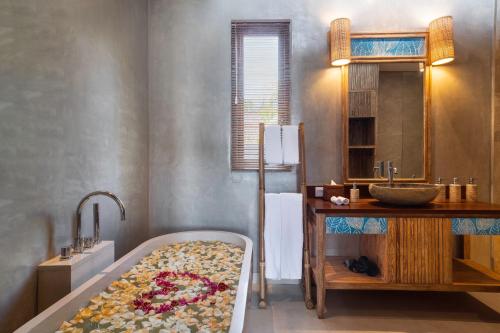 a bathroom with a bath tub and a sink at The Sankara Beach Resort - Nusa Penida in Nusa Penida